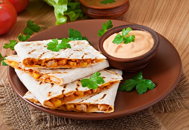 Mexican Quesadilla sliced with vegetables and sauces on the table