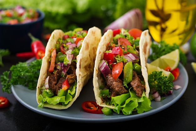 Mexican tacos with beef in tomato sauce and salsa