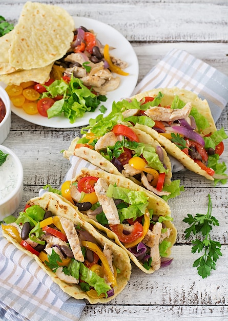 Mexican tacos with chicken, bell peppers, black beans and fresh vegetables