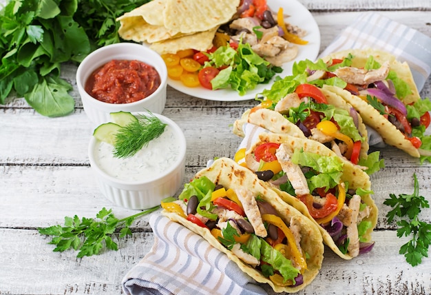 Mexican tacos with chicken, bell peppers, black beans and fresh vegetables