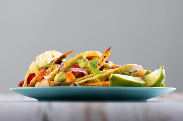 Mexican tacos with shrimpguacamole and vegetables on wooden table