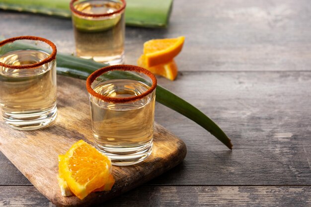 Mezcal Mexican drink with orange slices and worm salt on wooden table