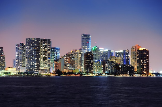 Miami city skyline panorama at dusk with urban skyscrapers over sea with reflection