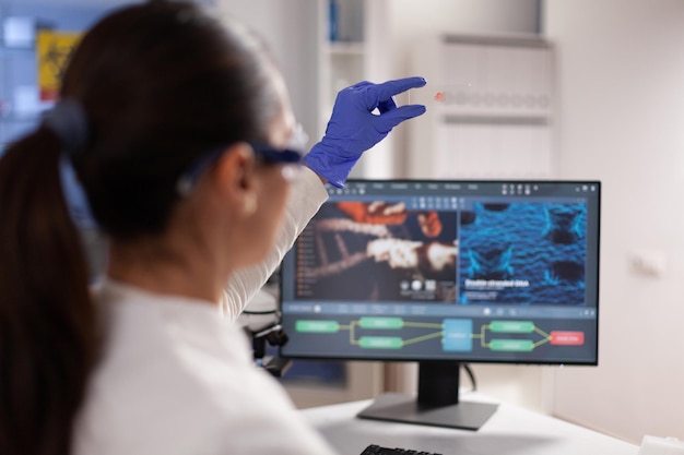 Free photo microbiologist scientist woman holding slice with blood sample during hematology experiment working in biochemical hospital laboratory. specialist doctor with medical glove analyzing dna test results