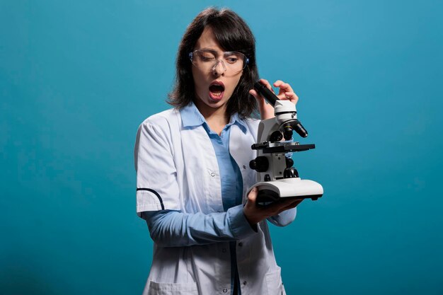 Microbiology expert with shock expression analyzing scientific discovery using modern microscope. Amazed researcher investigating bacteria experiment results while using magnifying instrument.