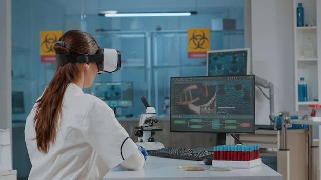 Microbiology specialist using vr glasses in laboratory to work on science experiment for development. Scientist working with virtual reality headset in research lab for futuristic presentation