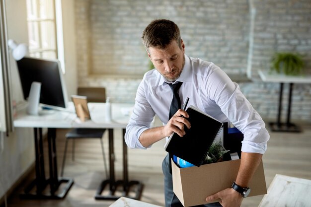 mid adult businessman getting fired and packing his stuff in the office