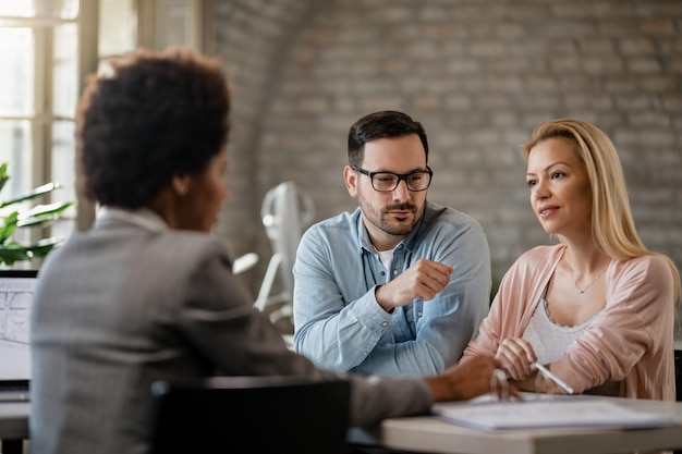 Mid adult couple talking with financial advisor while having consultations in the office