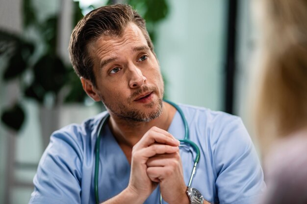 Mid adult doctor communicating with his patient during medical exam at hospital