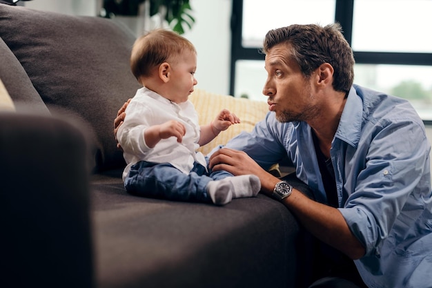 Бесплатное фото Отец среднего возраста общается со своим маленьким сыном и разговаривает с ним в гостиной