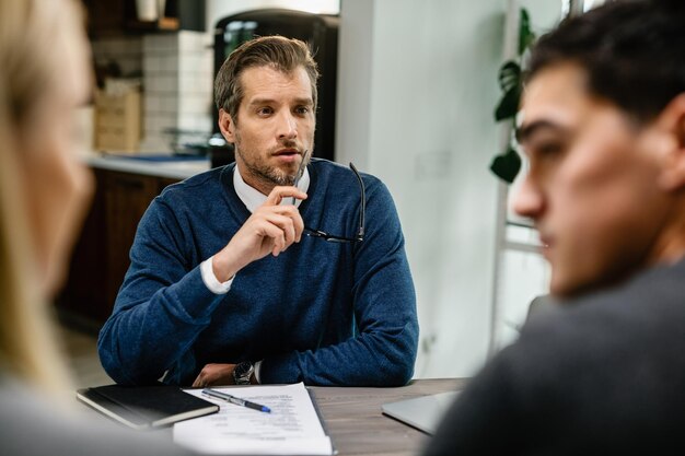 Mid adult insurance agent talking to a couple while having a meeting at their home