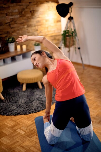 Mid adult sportswoman stretching during home workout