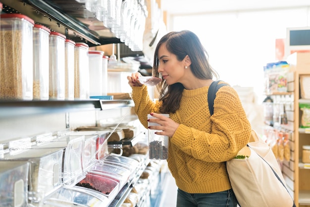 食料品店の棚でスクープで食べ物の匂いを嗅ぐ中年の大人の女性