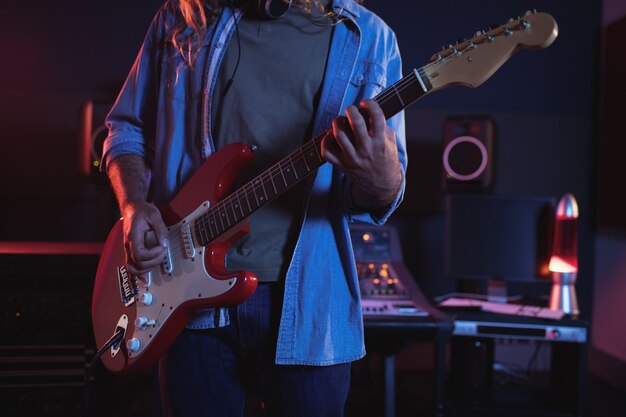 Mid section of audio engineer playing electric keyboard