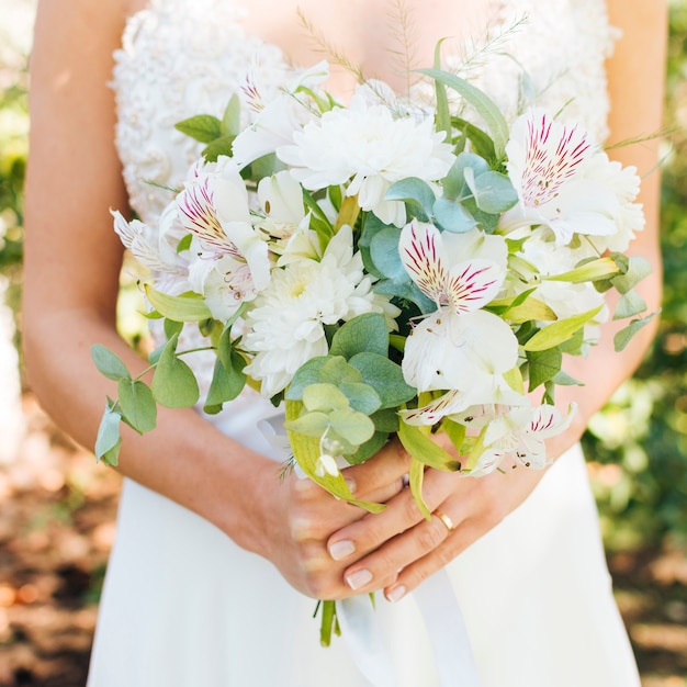Mid section of a bride's hands holding beautiful flower bouquet