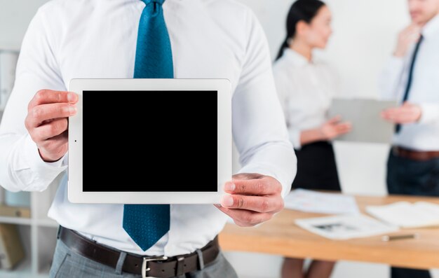 Средний раздел бизнесмена показывая таблетку пустого экрана цифровую на рабочем месте