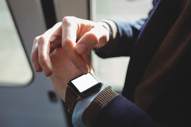 Mid-section of businessman using smartwatch while travelling