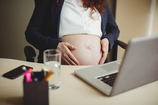 Mid-section of businesswoman holding her belly
