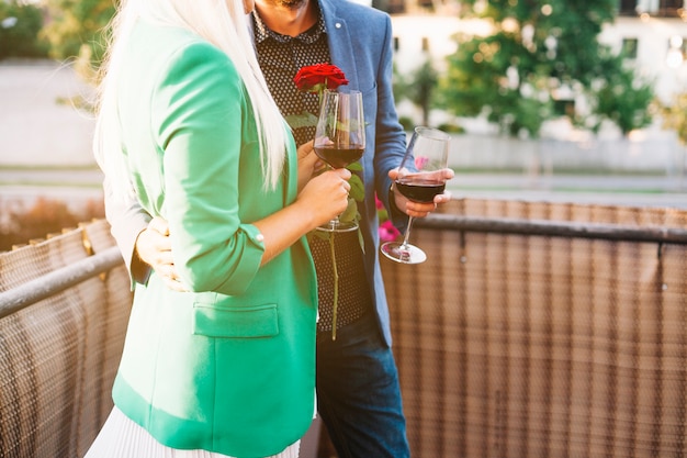 Free photo mid section of couple holding wine glasses