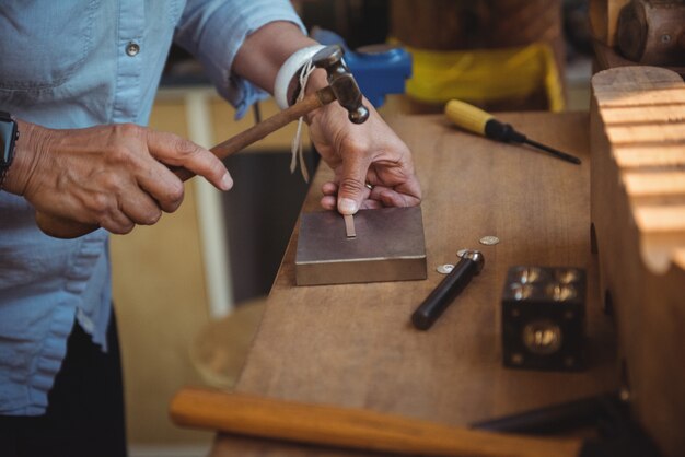 Mid-section of craftswoman using hammer