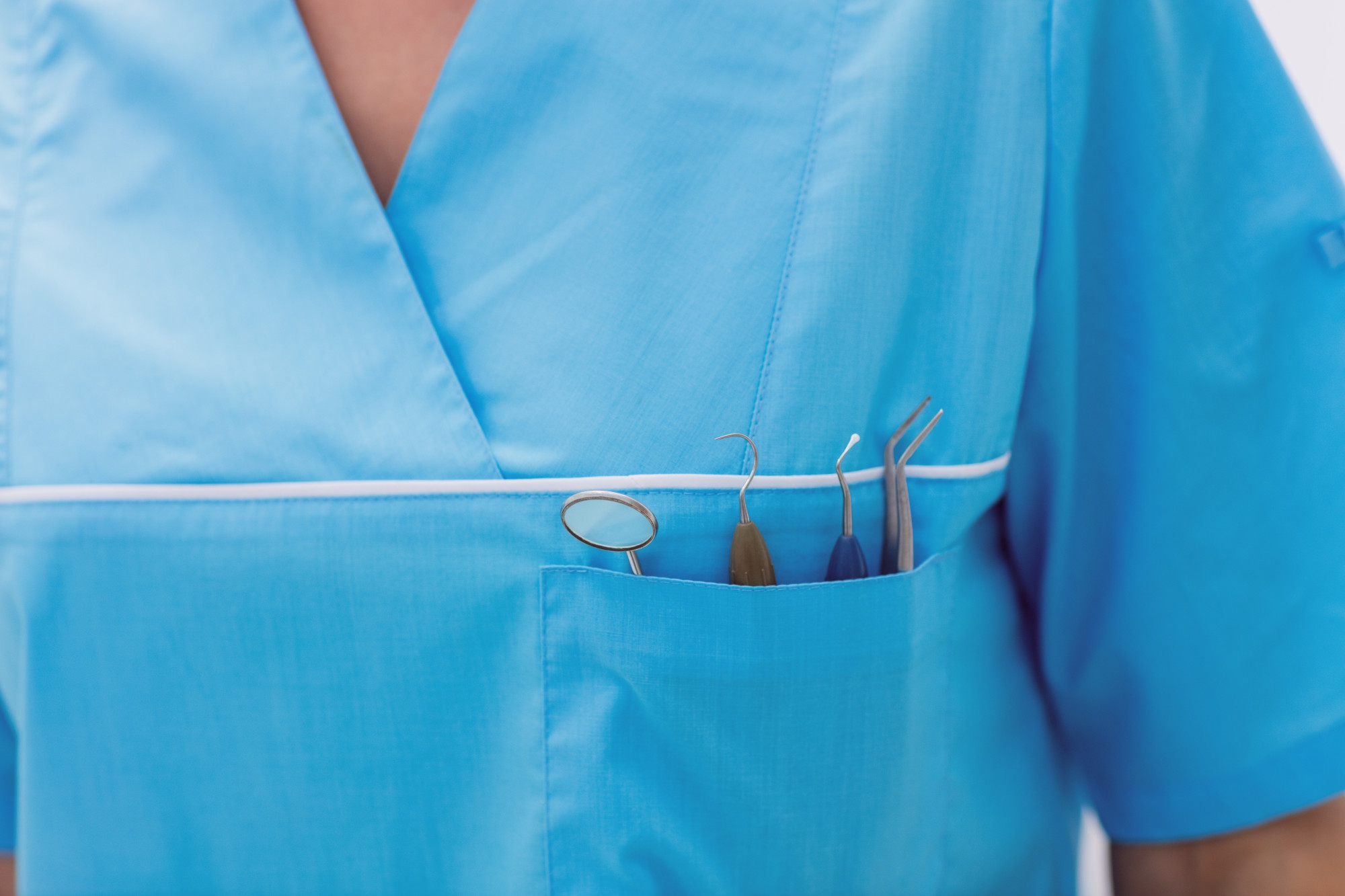 Mid section of dentist carrying dental tools in pocket