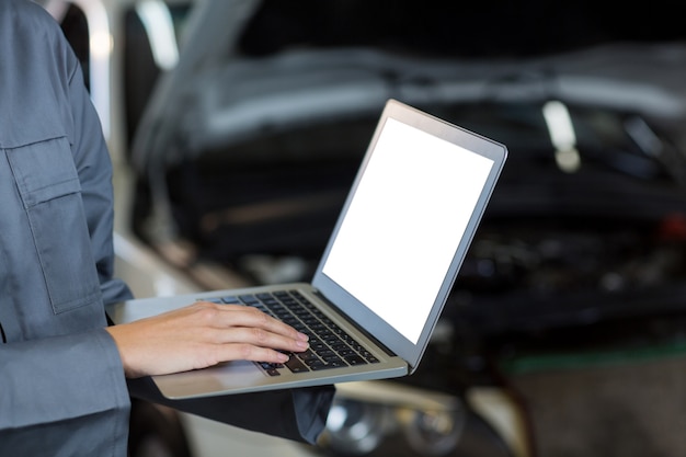 Free photo mid-section of female mechanic using laptop