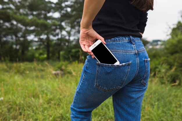 청바지 주머니에서 휴대 전화를 제거하는 여성의 중간 부분