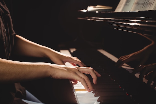 Free photo mid-section of female student playing piano