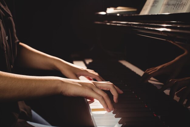 Mid-section of female student playing piano