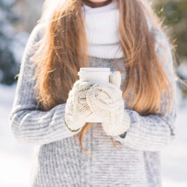 使い捨てのコーヒーカップを保持している女性の獣医師の中間部