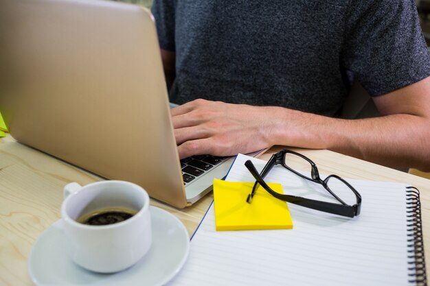 Mid-section of male business executive using laptop