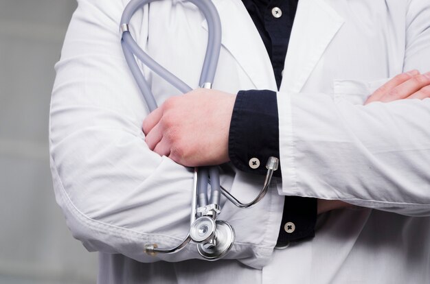 Mid section of male doctor's hand holding stethoscope in hand