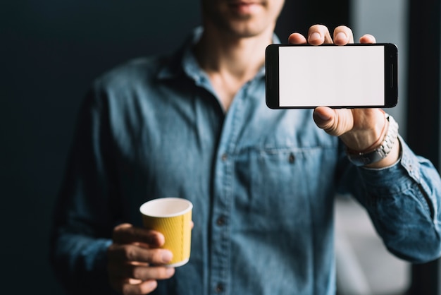 휴대 전화 화면을 보여주는 일회용 커피 컵을 들고 남자의 중간 부분