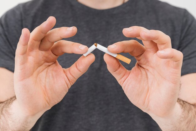 Mid section of a man's hand breaking the cigarette