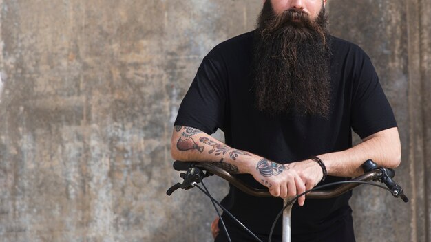 Mid section of a man sitting on bicycle against concrete backdrop