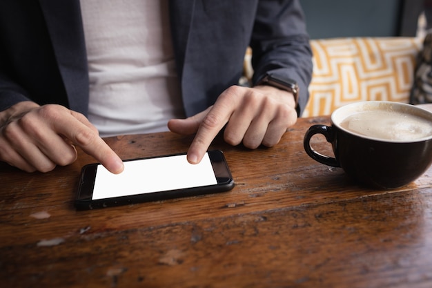 Mid section of man using digital tablet while having coffee