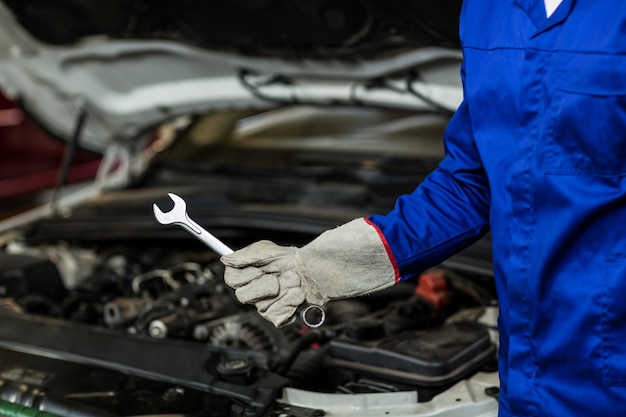 Free photo mid-section of mechanic holding wrench tool