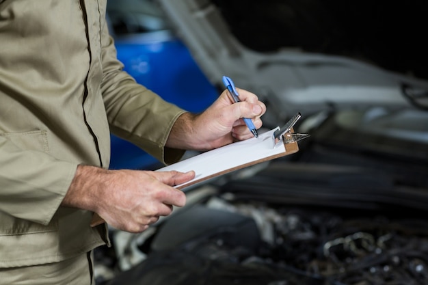 Free photo mid-section of mechanic preparing a check list