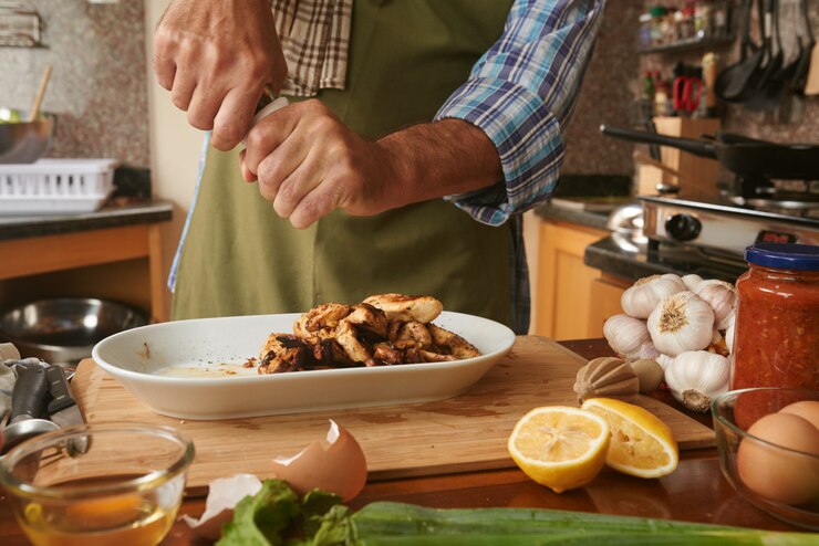 Free Photo mid section og anonymous cook seasoning dish with pepper