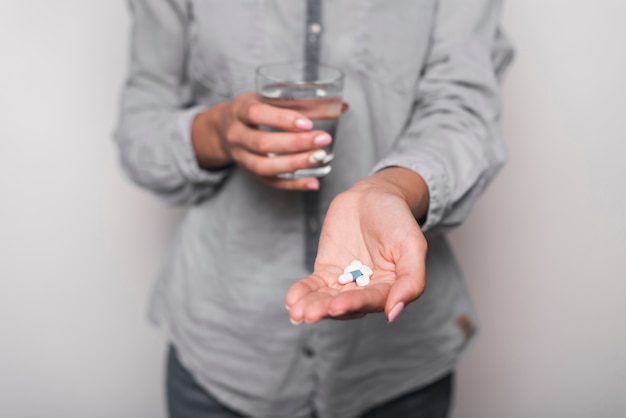 Mid section of sick woman taking pills against gray background