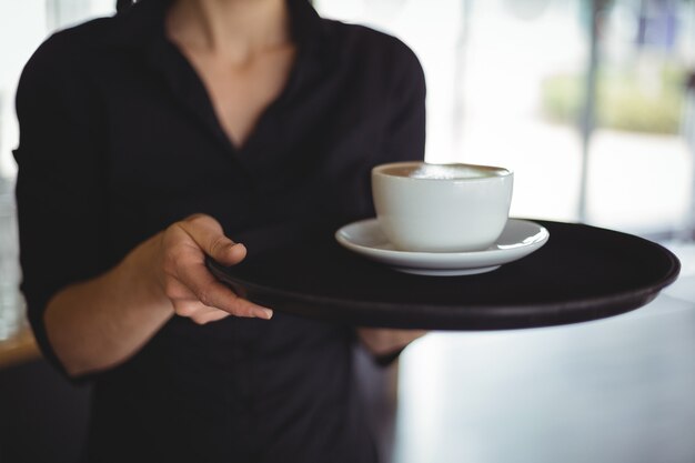 Mid section of waitress standing with cup of coffee