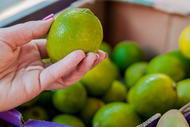 Sezione centrale di donna che acquista calce dolce nel supermercato. donna che acquista frutta nel mercato verde organico. donna che sceglie calce fresca