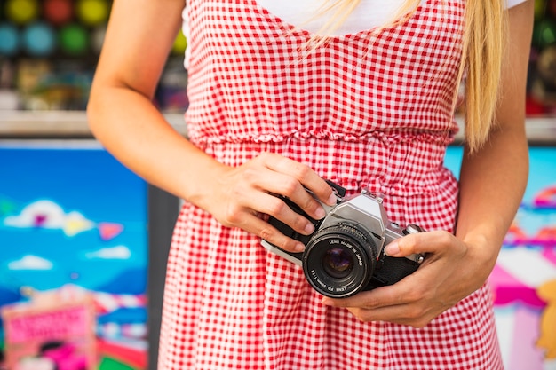 Free photo mid section of woman holding camera in hand