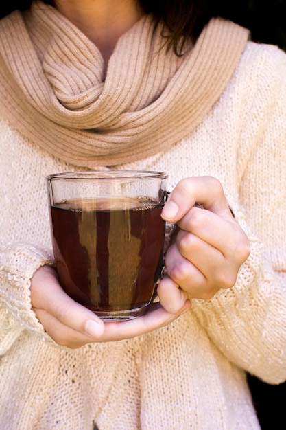 Mid section of a woman holding transparent mug of herbal tea