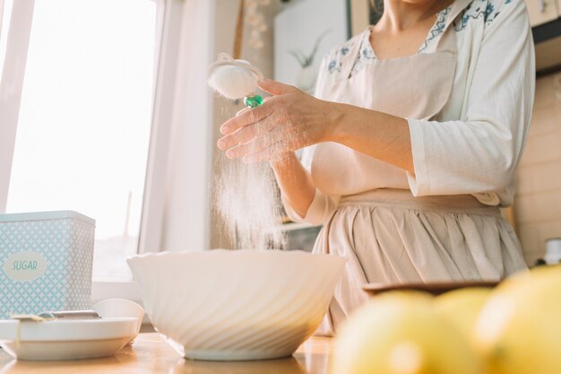Средняя часть женщины на кухне готовит тесто из муки, чтобы сделать пирог
