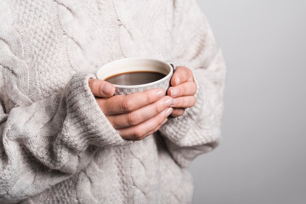 Mid section of woman in woolen clothes holding coffee cup