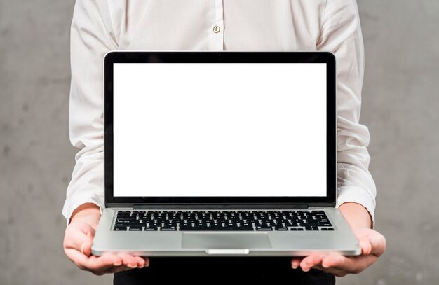 Mid-section of a young businesswoman holding laptop in hand showing white screen display