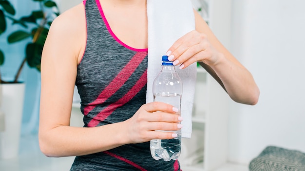 Средняя часть молодой женщины закрывает бутылку с водой