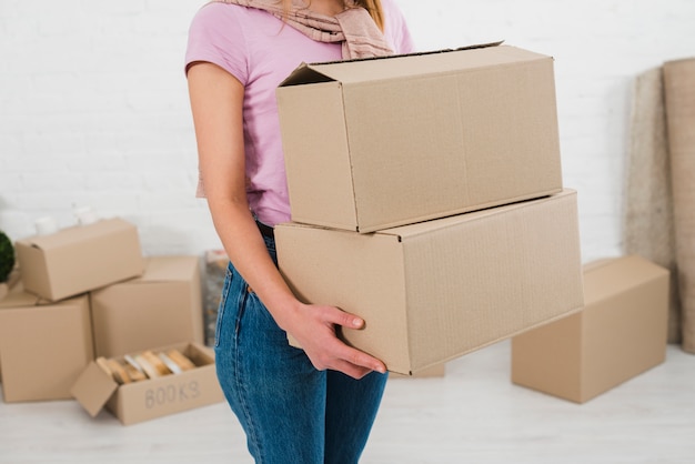 Mid section on a young woman holding stack of cardboard boxes