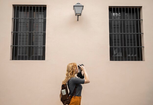 Середина короткой женщины, делающей фотографии с камерой